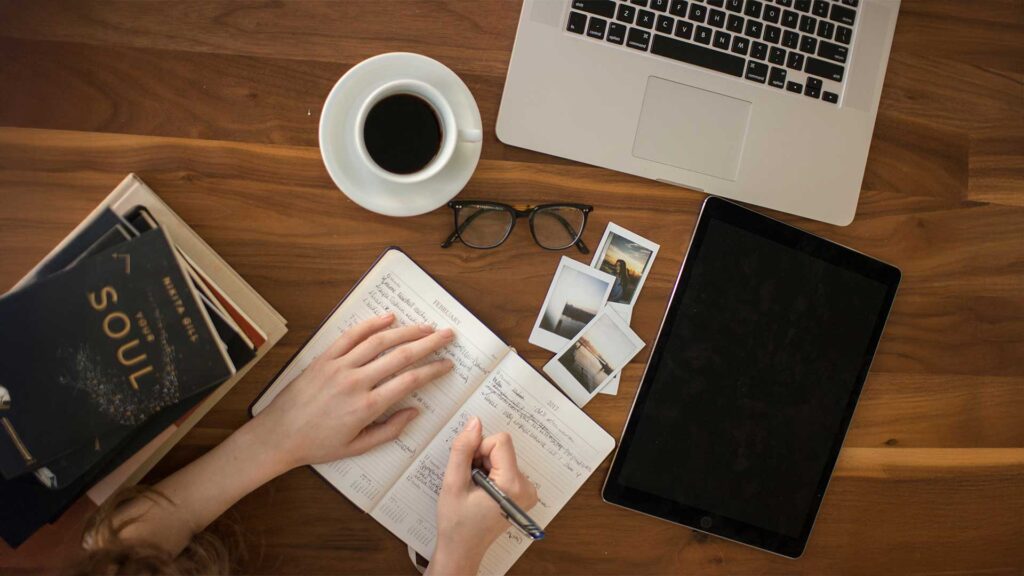 Person taking notes while drinking coffee